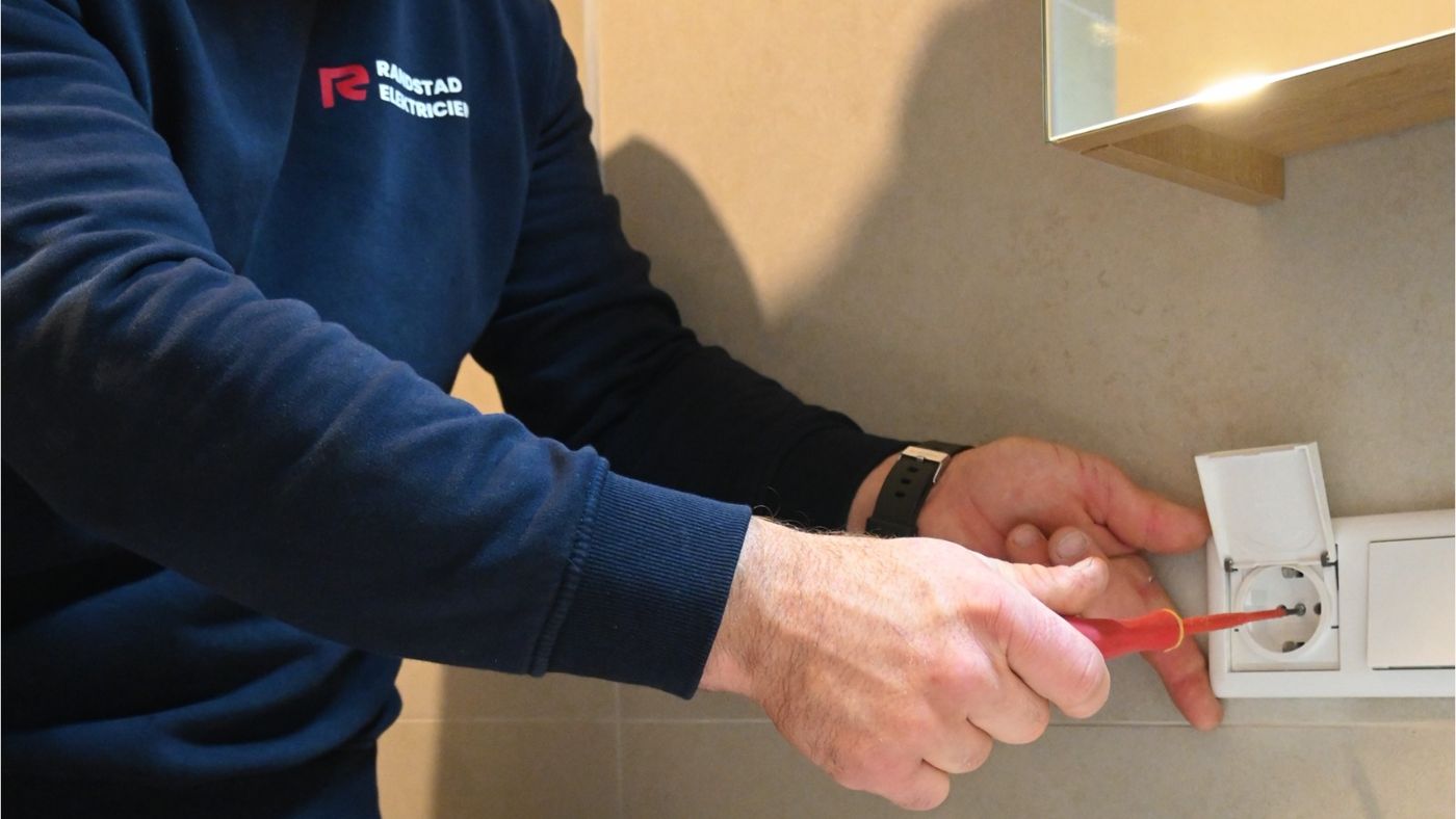 Monteur van Randstad Elektricien sluit een stopcontact aan
